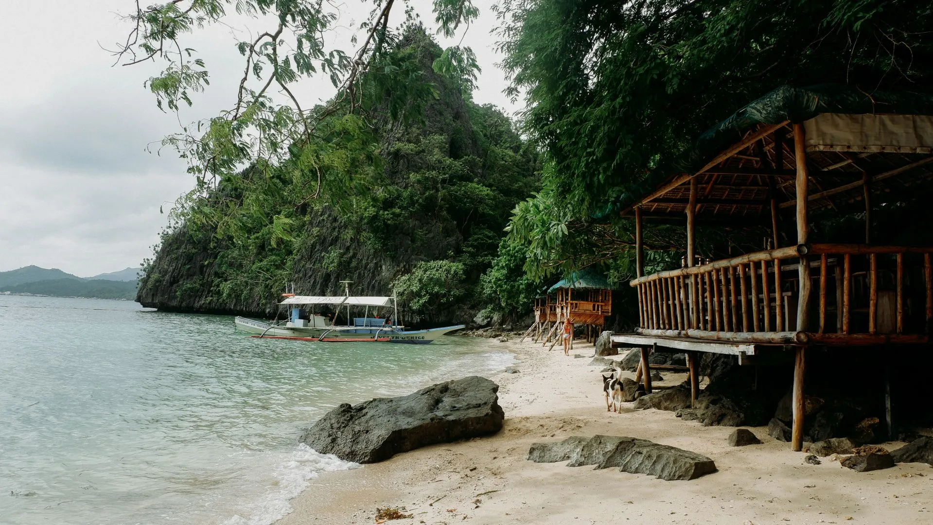 Nipa cottages on a quiet cove beside a limestone cliff